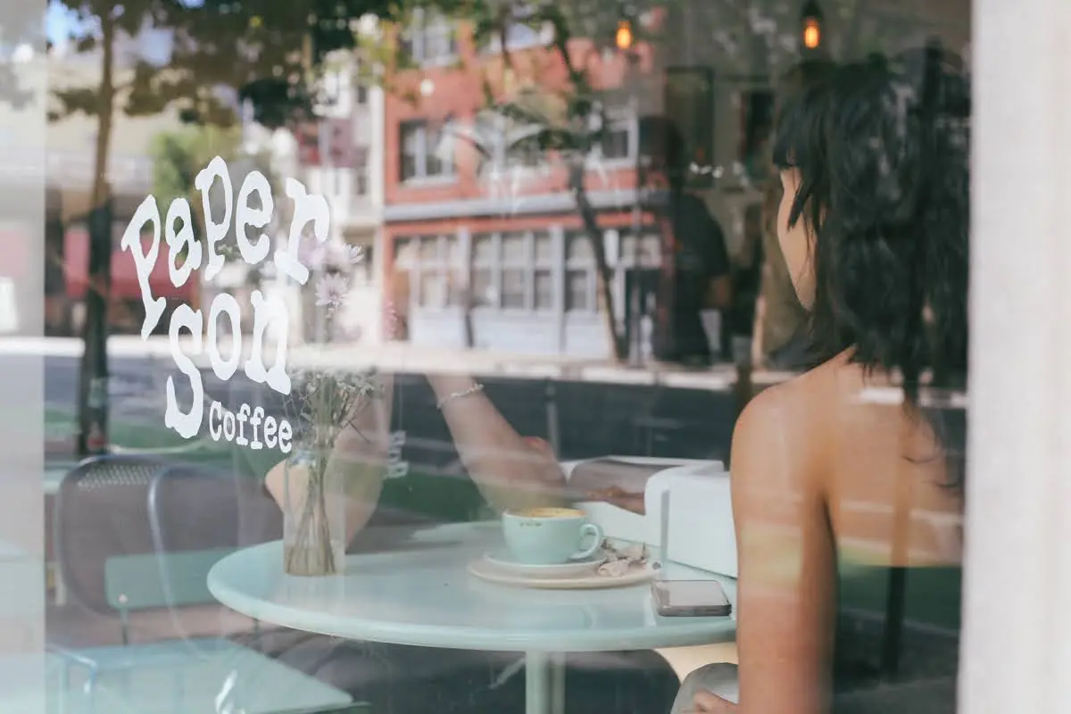 Customer with coffee at the window of Paper Son Coffee Downtown